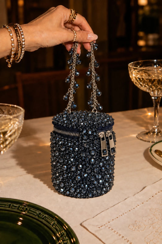 Designer charcoal blue handbag with intricate handcrafted beadwork and an embellished chain handle.