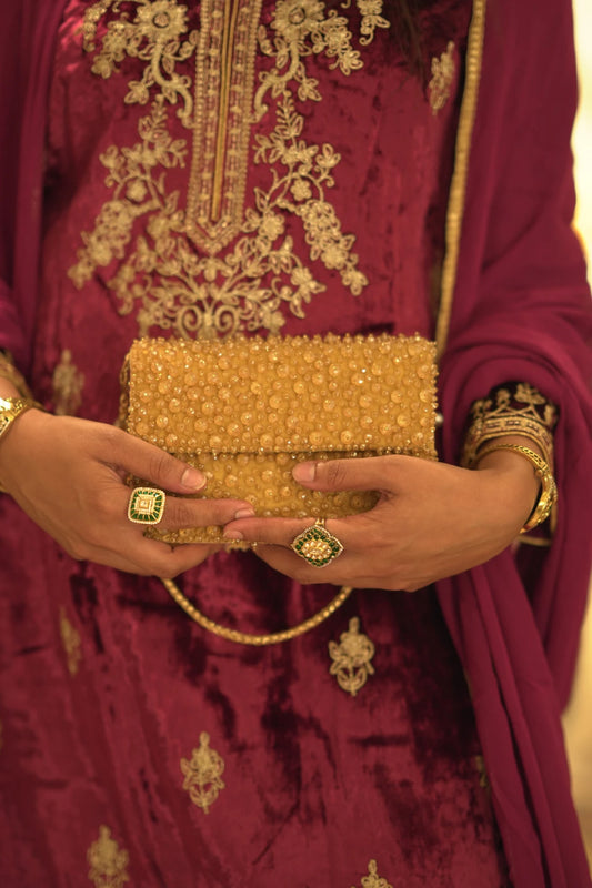Designer golden shoulder bag styled with a bridal lehenga