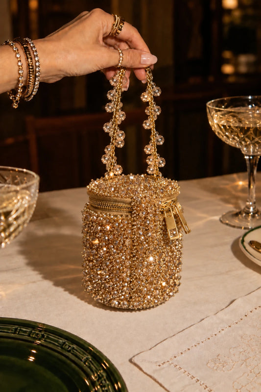 Designer golden handbag with intricate handcrafted beadwork and an elegant embellished chain handle.