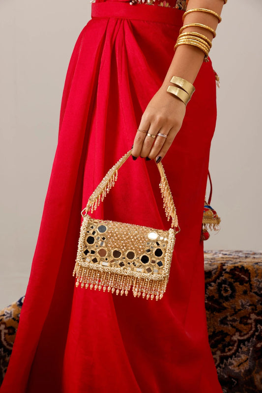 Designer golden shoulder bag styled with a bridal lehenga