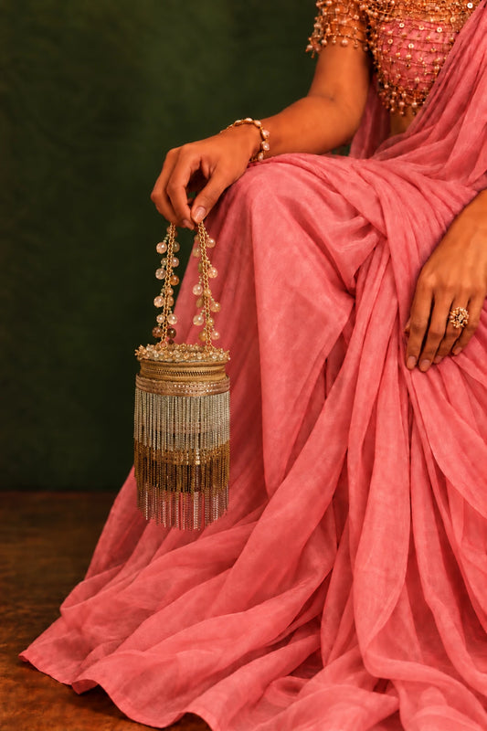 Designer gold and silver cylindrical handbag with shimmering metallic fringe detailing and an embellished chain handle.