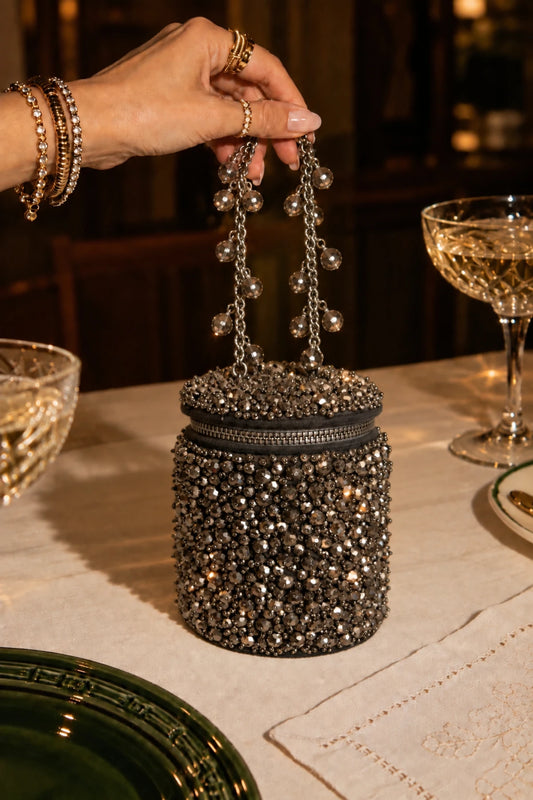 Designer grey handbag with intricate handcrafted beadwork and an elegant embellished chain handle.