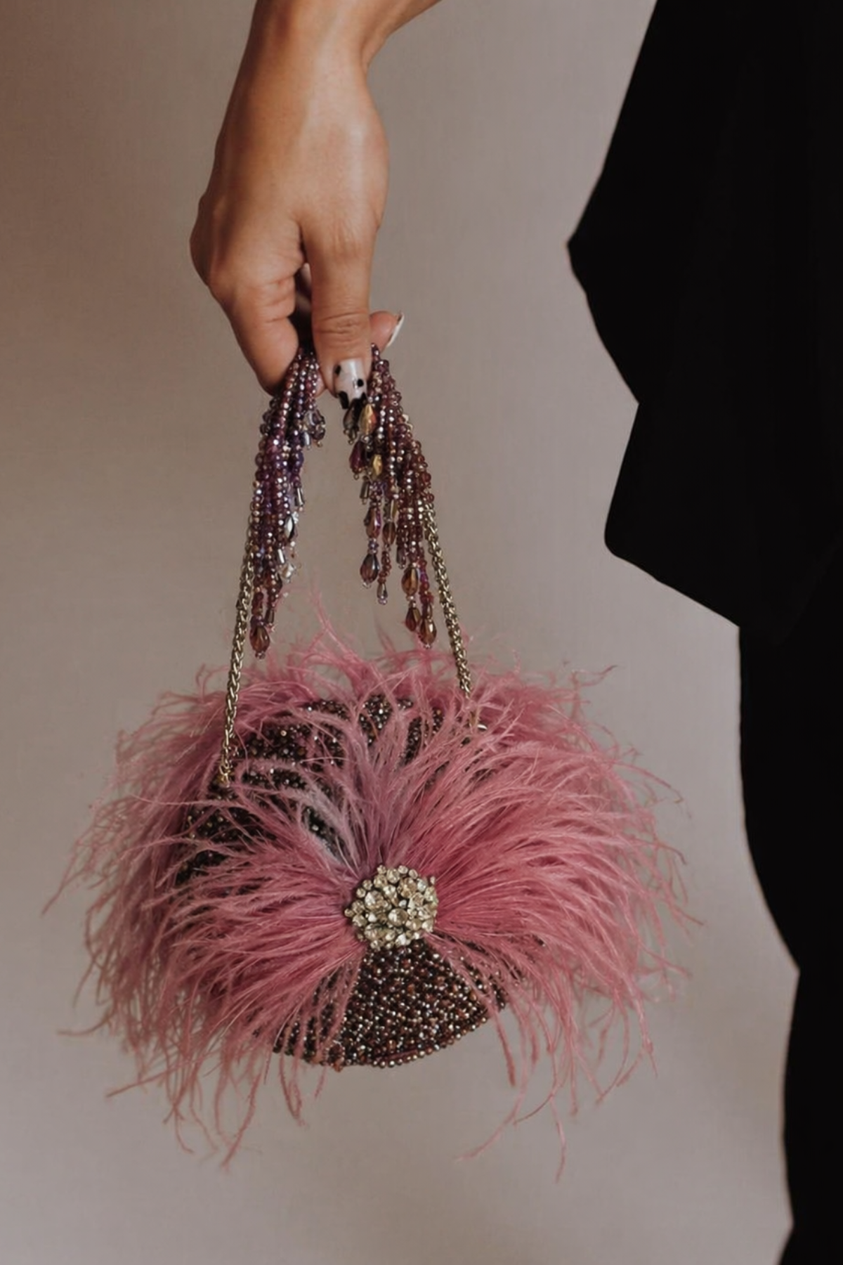 Gift-worthy pink party bag featuring statement feather detailing and luxe craftsmanship