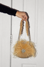 Glam gold night-out bag combining couture-inspired feathers with modern sparkle