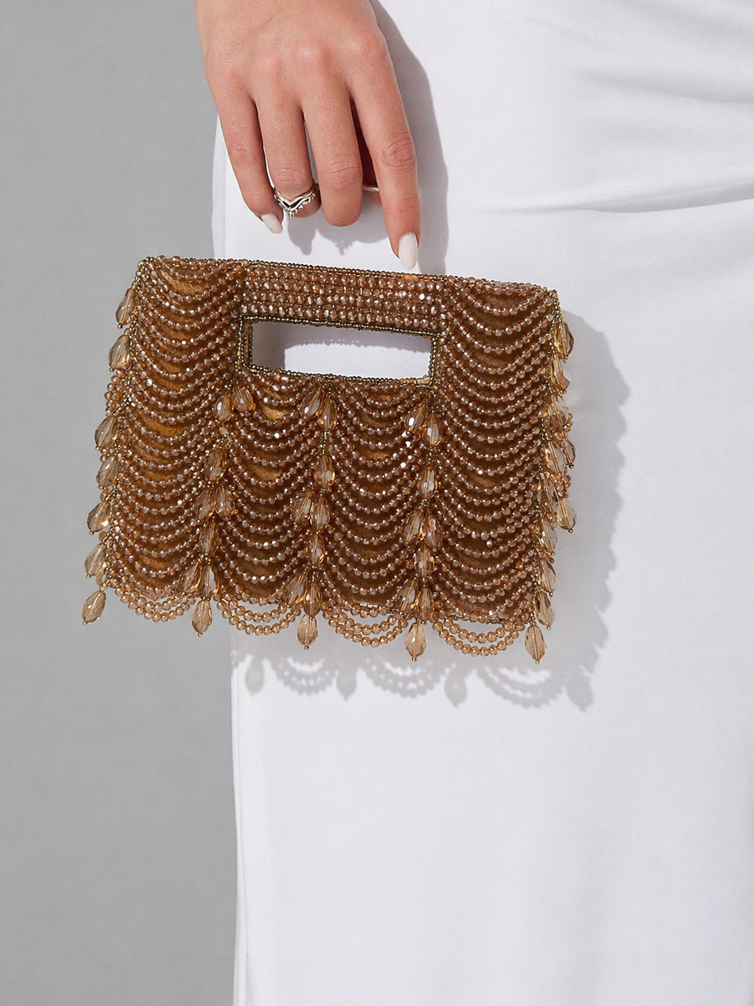 Gold chain embellished purse featuring statement drape detailing and sophisticated sparkle
