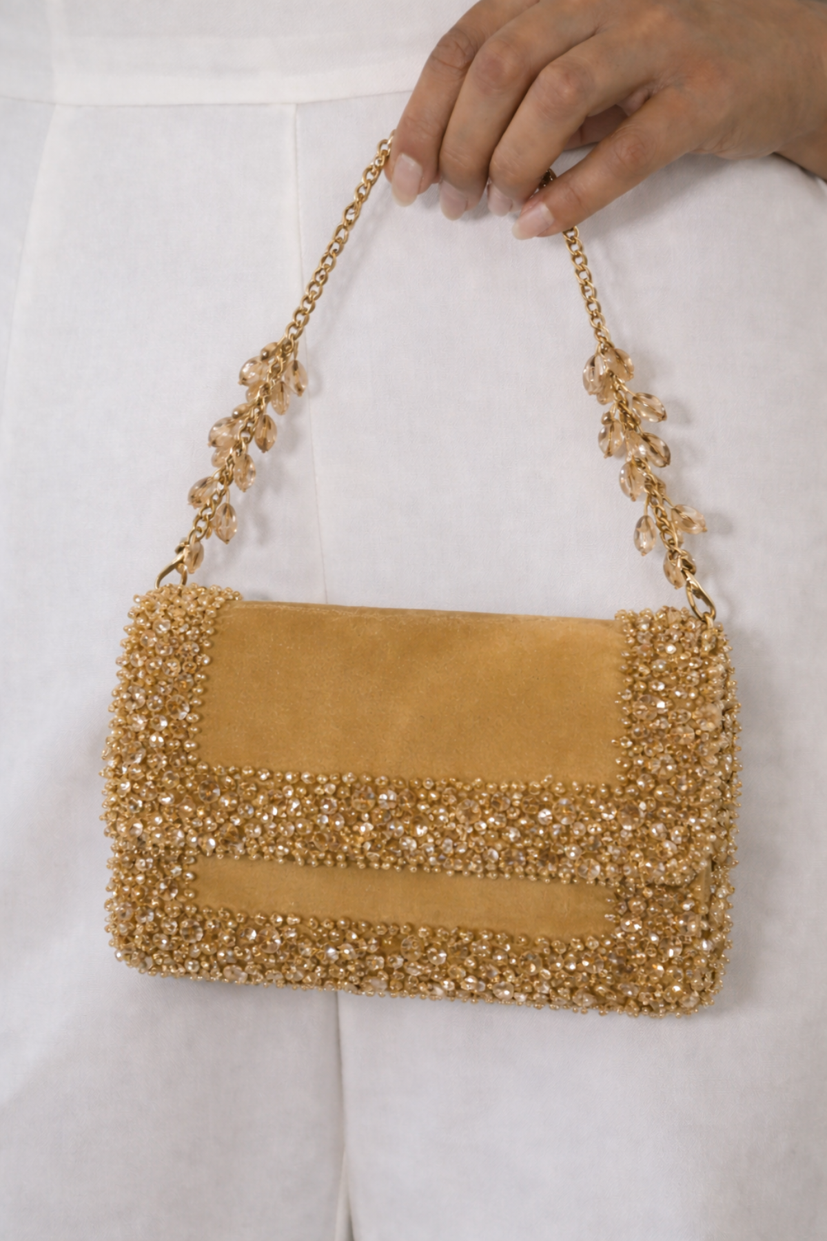 Luxury gold wedding guest purse featuring handcrafted stone embellishments and rich suede texture