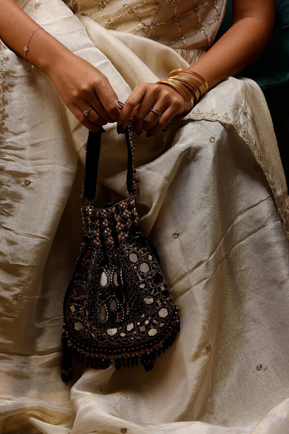 Black mirror work potli bag paired with a silk saree