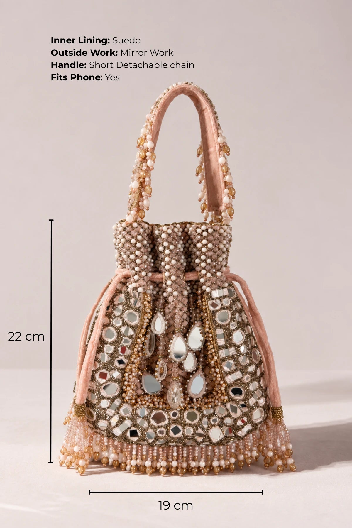 Baby pink mirror work potli handbag featuring intricate handcrafted detailing for Indian weddings and celebrations.