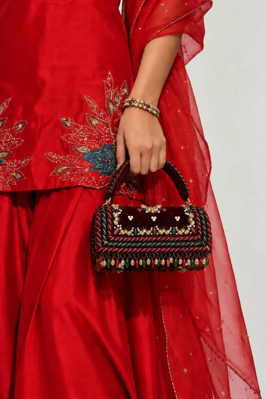 Designer red clutch bag with handcrafted bead, pearl and stone embellishments on a luxurious deep red base.