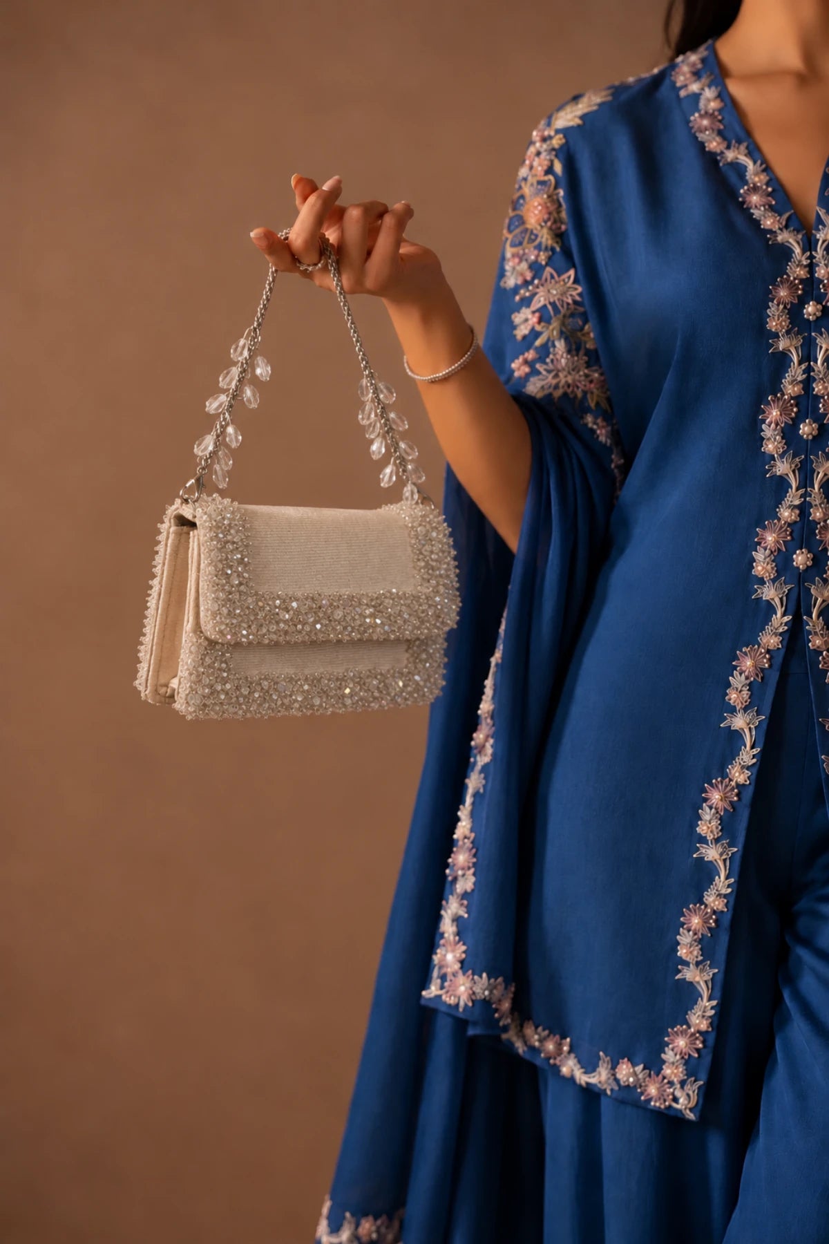 Designer white handbag featuring handcrafted crystal and bead embellishments with an elegant contemporary finish.